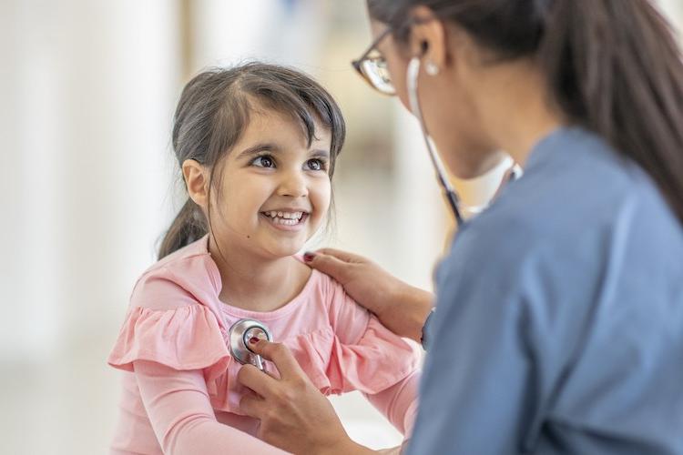 Medical professional listening to pediatric girl's heartbeat